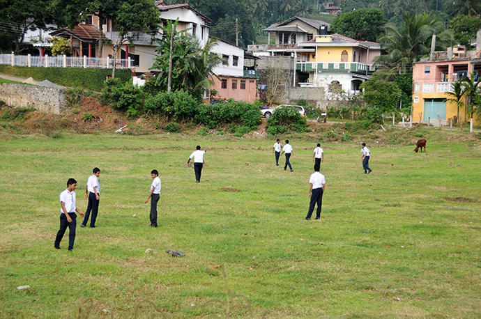 Children playing soccer in their school uniforms-probably their sports lesson